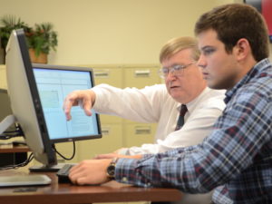 Professor working with student at a computer