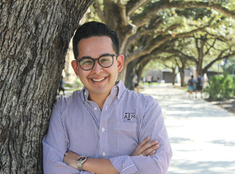 Student leaning against tree