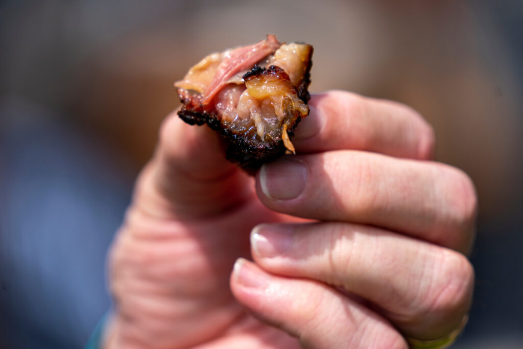 hand holding a bite-sized piece of brisket